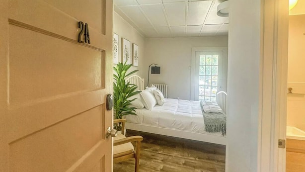 A bedroom with a bed, a radiator, a window, and a door.