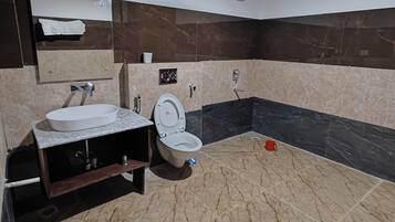 Un baño con suelo de mármol, lavamanos, inodoro y ducha.