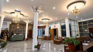 Eine moderne Hotelhalle mit hohen Decken, Kronleuchtern und großen Fenstern.