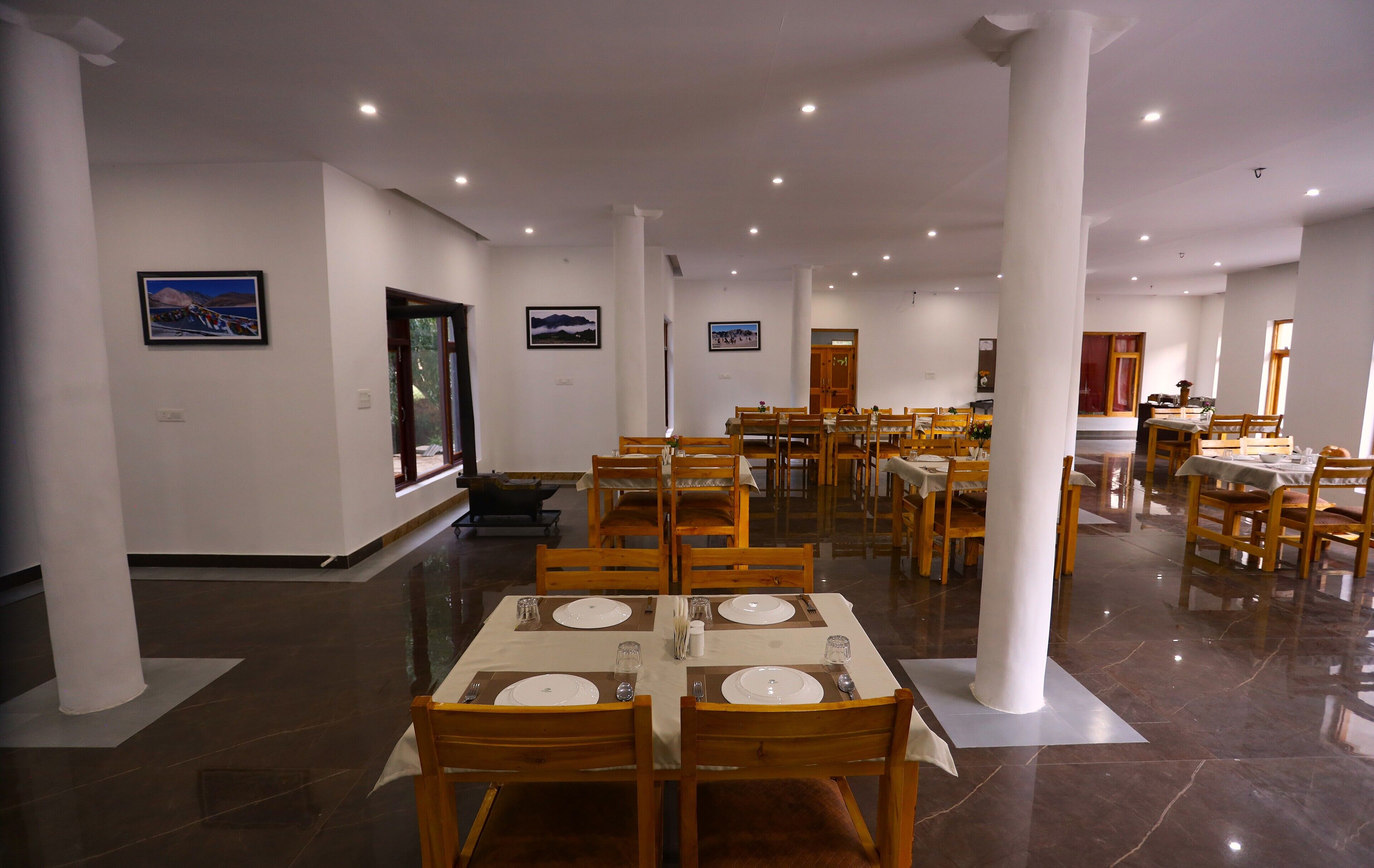 Un amplio comedor con varias mesas y sillas, paredes blancas e iluminación en el techo.