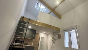 A compact, modern interior with a loft-style sleeping area, a kitchenette, and a small bathroom. - Self-contained studio near Paris (Vitry-sur-Seine)