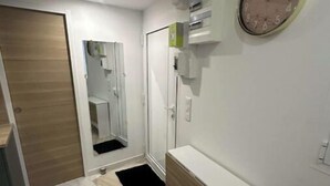 A modern bathroom with a mirror, sink, and clock on the wall. - Self-contained studio near Paris (Vitry-sur-Seine)