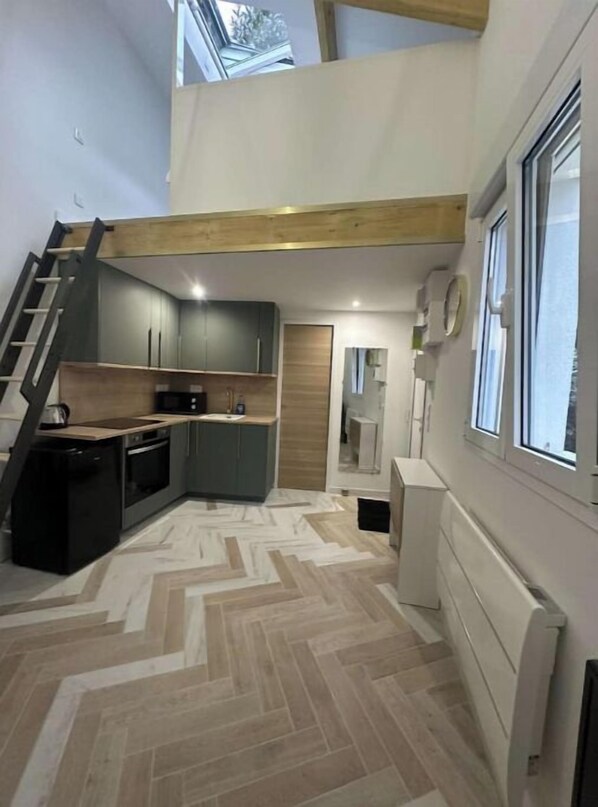 Una cucina compatta con elettrodomestici moderni, un pavimento a spina di pesce e un soffitto in legno.