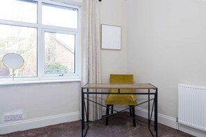 Ein Eckzimmer mit Fenster, Tisch, Stuhl und Heizkörper.