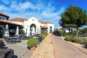 A building with outdoor seating, a paved walkway, and a stone wall.