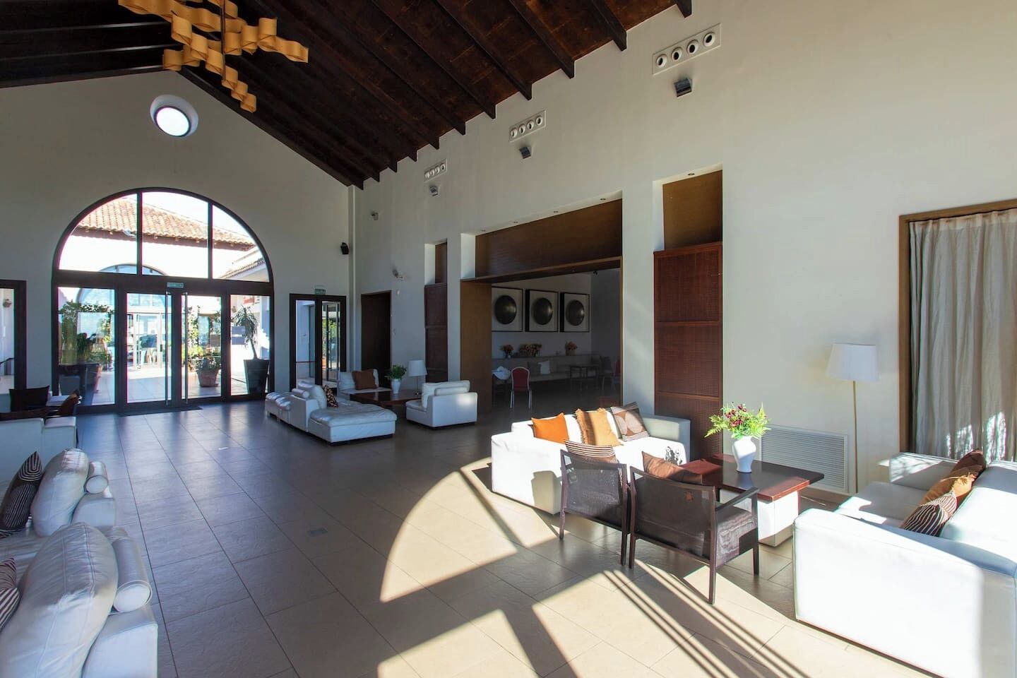 A spacious living area with a high ceiling, large windows, and a view of the outdoors.