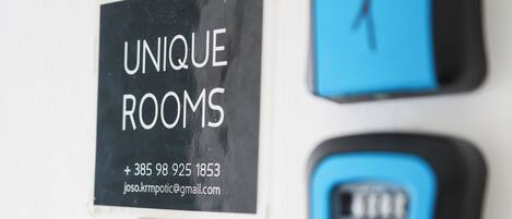 A wall-mounted sign for "Unique Rooms" with a contact number and email.