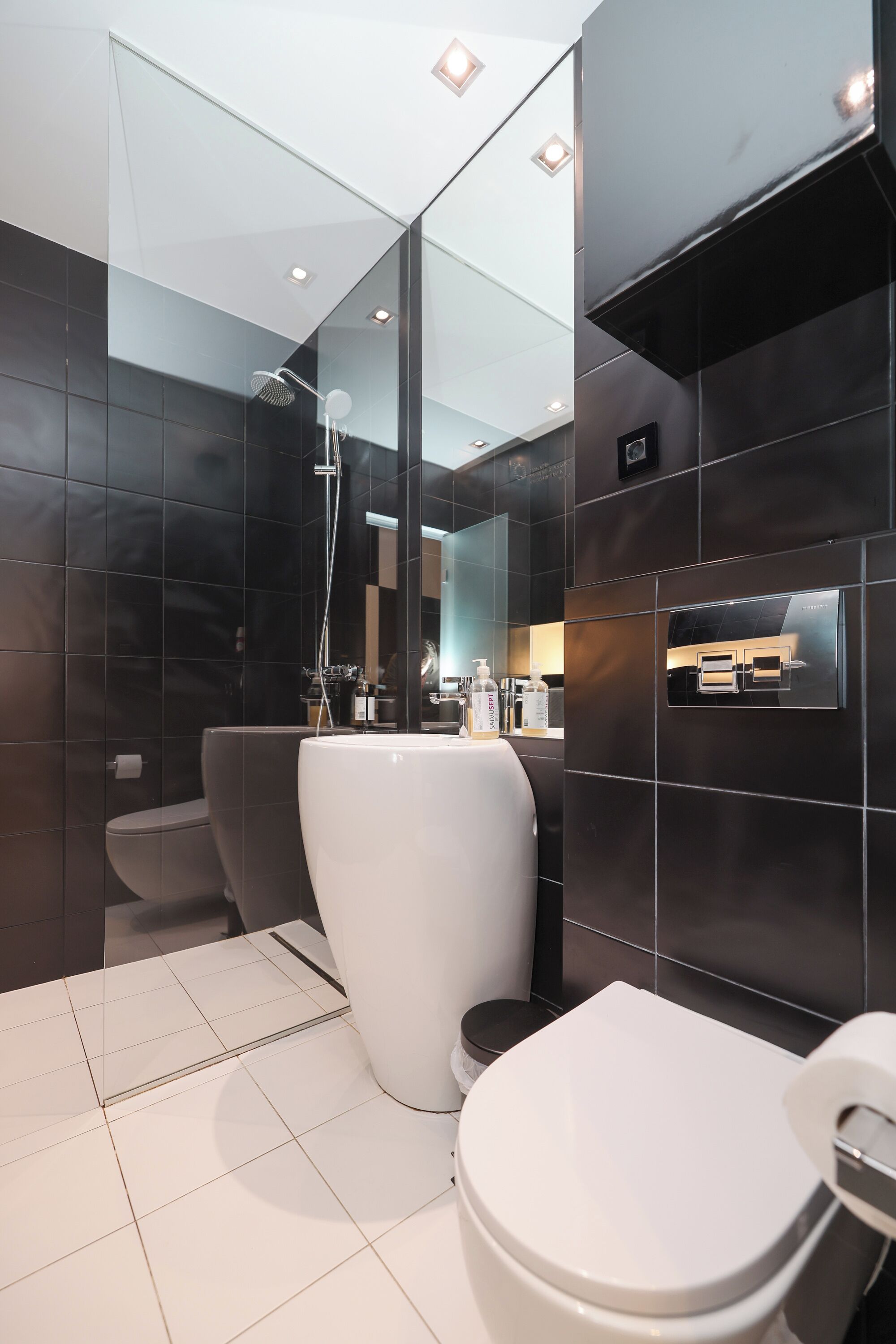 Un bagno moderno con un water bianco, zona doccia e vanità con chiusura in vetro.