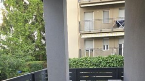 A balcony with a black metal railing, a grey floor, and a white air conditioning unit. - Bergamoinluxe (Bergamo)