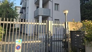 A gated entrance to a modern apartment building with balconies, a no parking sign, and a street lamp. - Bergamoinluxe (Bergamo)
