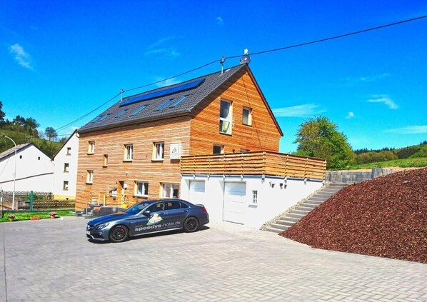 A two-story wooden building with a car parked in front. - Pitlane Apartments by corents (Herresbach)