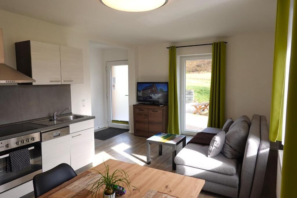 A modern kitchen with a built-in oven and a dining area with a wooden table and chairs.