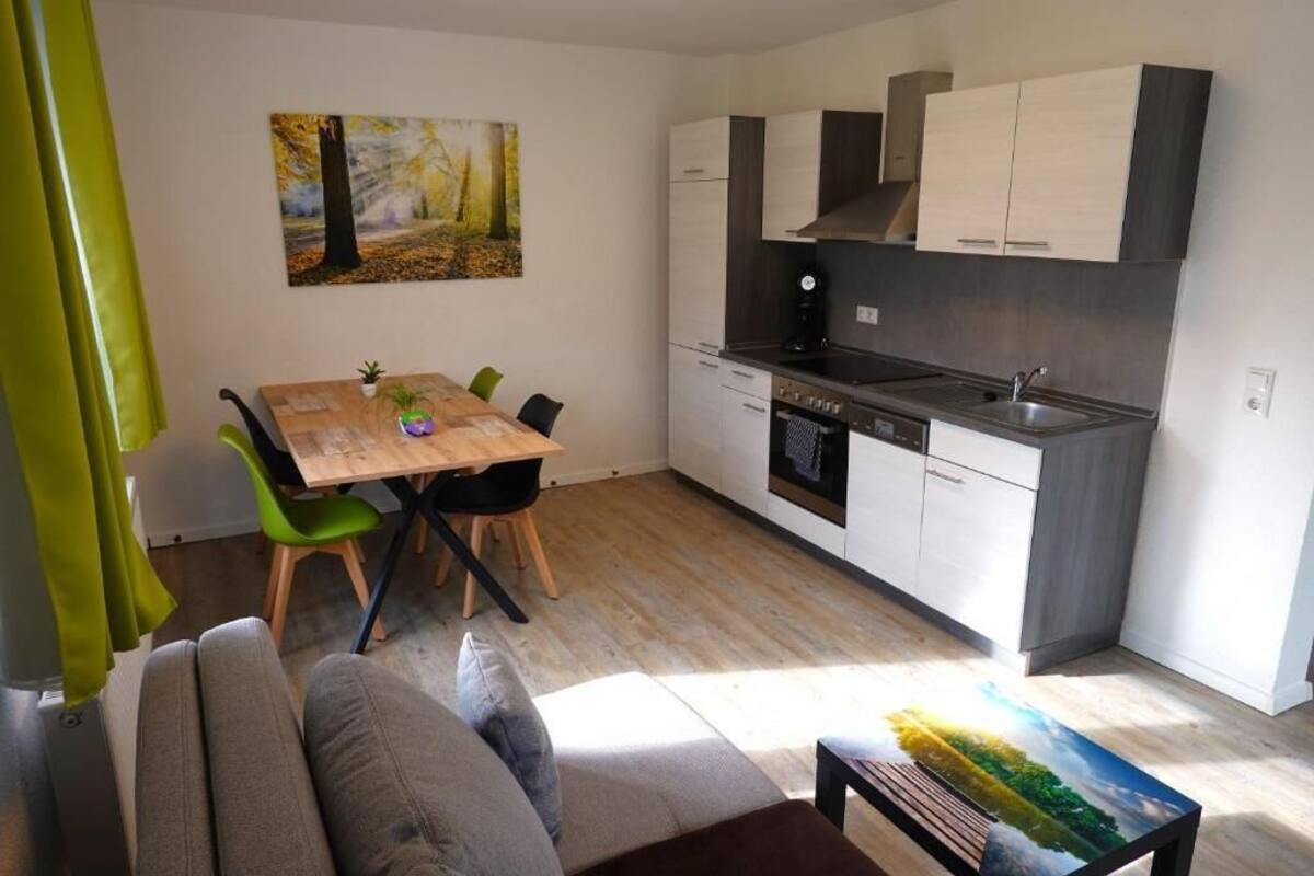 Eine moderne Küche mit weißen Schränken, einem Holzespeisetisch und einem Gemälde an der Wand.