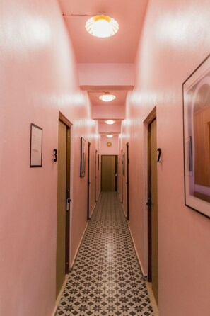 Un pasillo con paredes rosas, baldosas de suelo estampadas y puertas numeradas 2 y 3.
