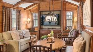 Ein gemütliches Blockhäuschen-Interieur mit Holzbalkendecke, einem Esstisch und einer Couch.