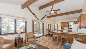 A spacious living area with a wooden ceiling, a dining table, and a kitchen area with wooden cabinets and a refrigerator.