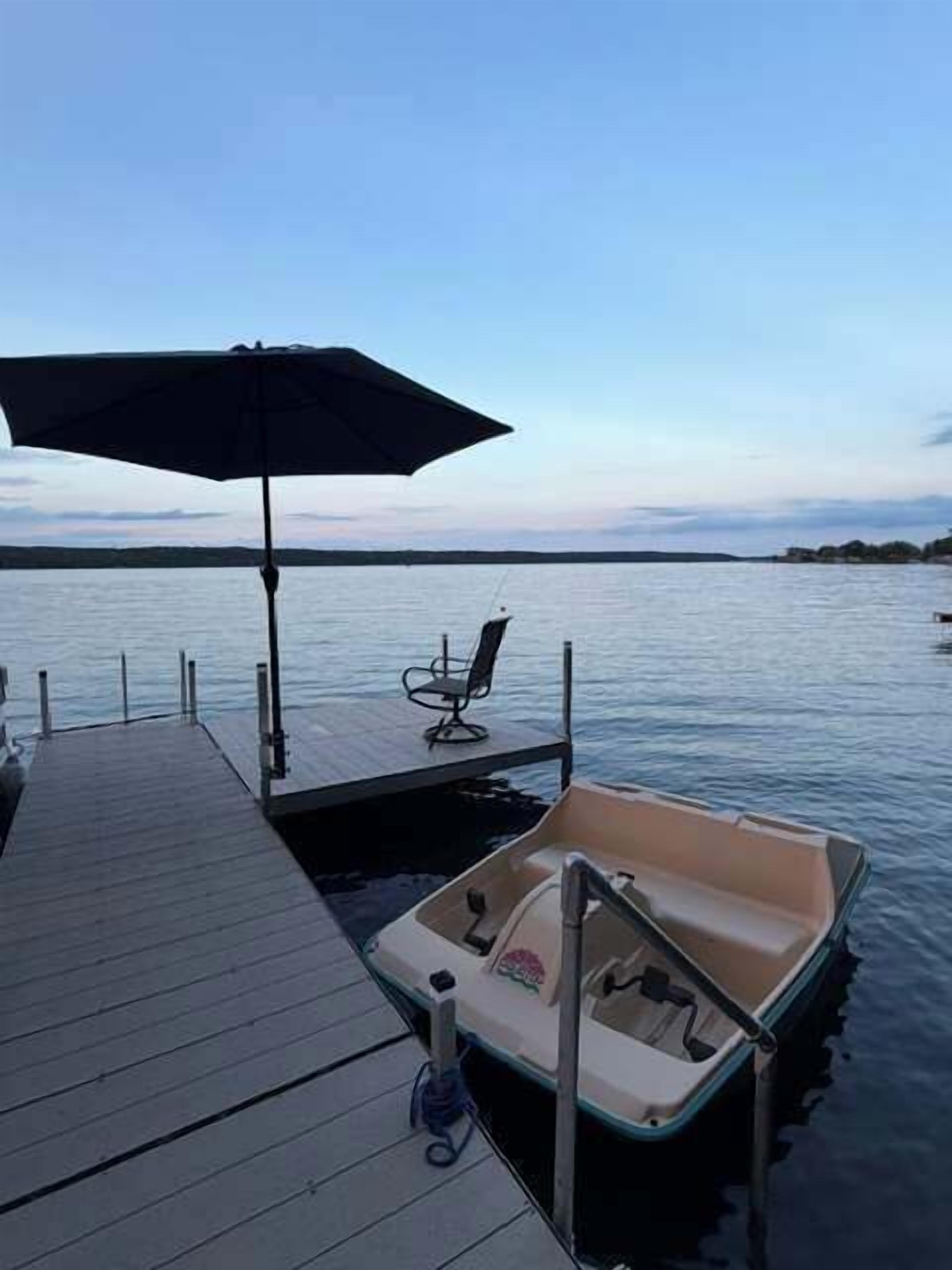 A dock with a boat, a chair, and an umbrella.