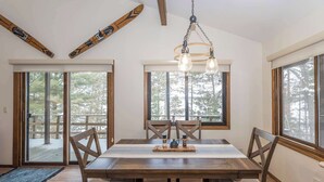 A dining area with a wooden table, four chairs, and a chandelier.