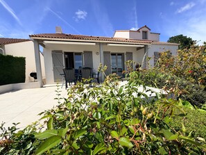 A two-story house with a patio, outdoor seating, and a garden.