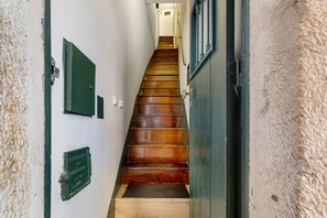 Eine Holztreppe führt zu einem Raum mit einer Tür und einem Fenster.