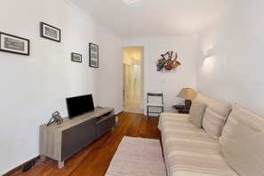 Ein modernes Wohnzimmer mit einer Couch, einem Fernseher und gerahmten Bildern an der Wand.
