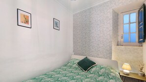 Et soveværelse med en seng, et sengebord med en lampe og to billeder i rammer på væggen.