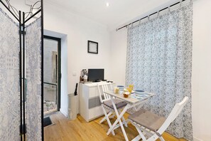 Ein kleines Zimmer mit Schreibtisch, Stuhl und einem Tisch mit Frühstücksgebäck.