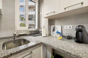 Eine Küche mit einer Granit-Arbeitsplatte, einer Edelstahl-Spüle und einer Kaffeemaschine.