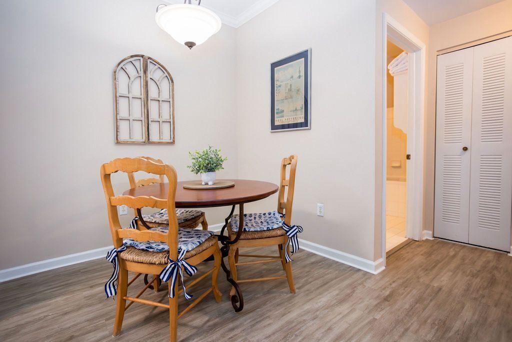 A dining area with a round table and four chairs, a potted plant, a wall-mounted picture, and a door leading to a closet.