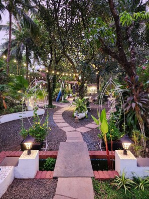 Um caminho de jardim com pedras para pisar, cercado por diversas plantas e árvores.