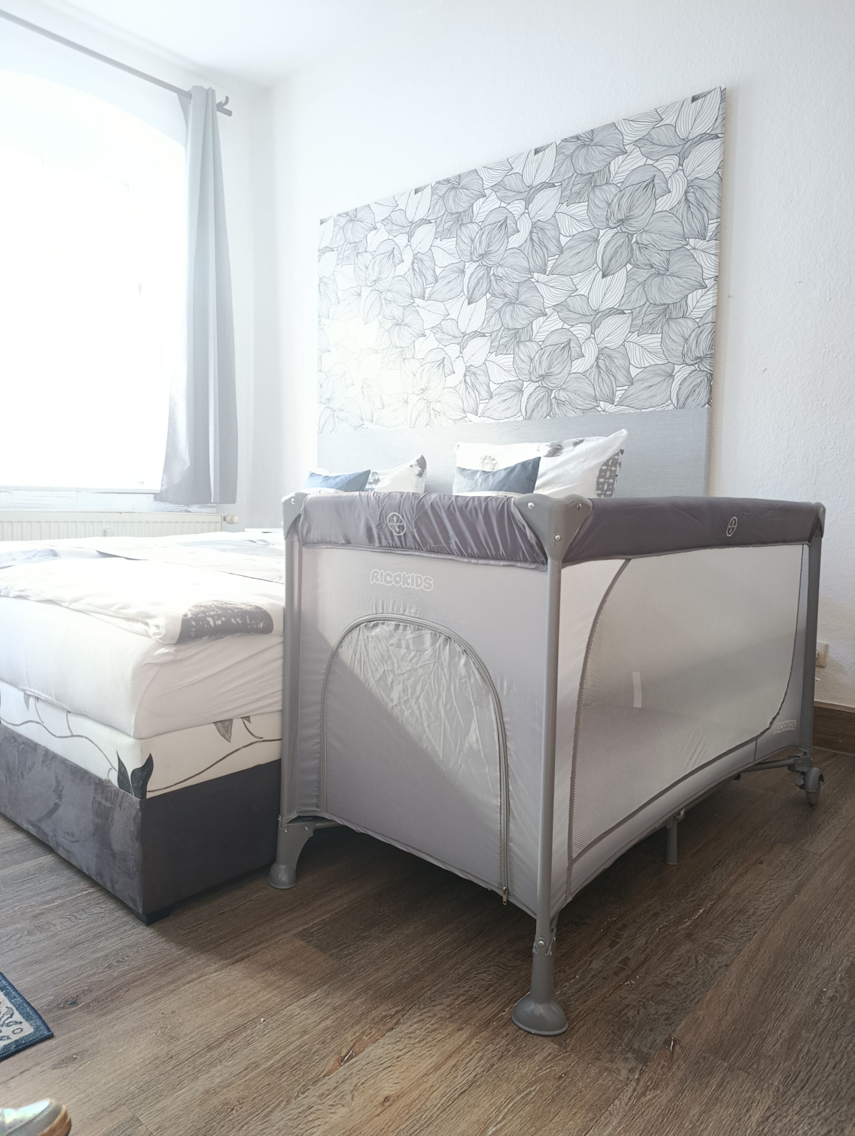 A bedroom with a bed, a canopy bed, a wall-mounted artwork, and a window with curtains.