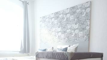 A bedroom with a bed, a canopy bed, a wall-mounted artwork, and a window with curtains.