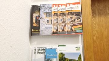Een muur met brochures voor de Vogtland en Thüringen regio's, inclusief reistips en lokale bezienswaardigheden.