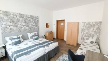 A bedroom with a bed, a wardrobe, a desk, and a mirror.