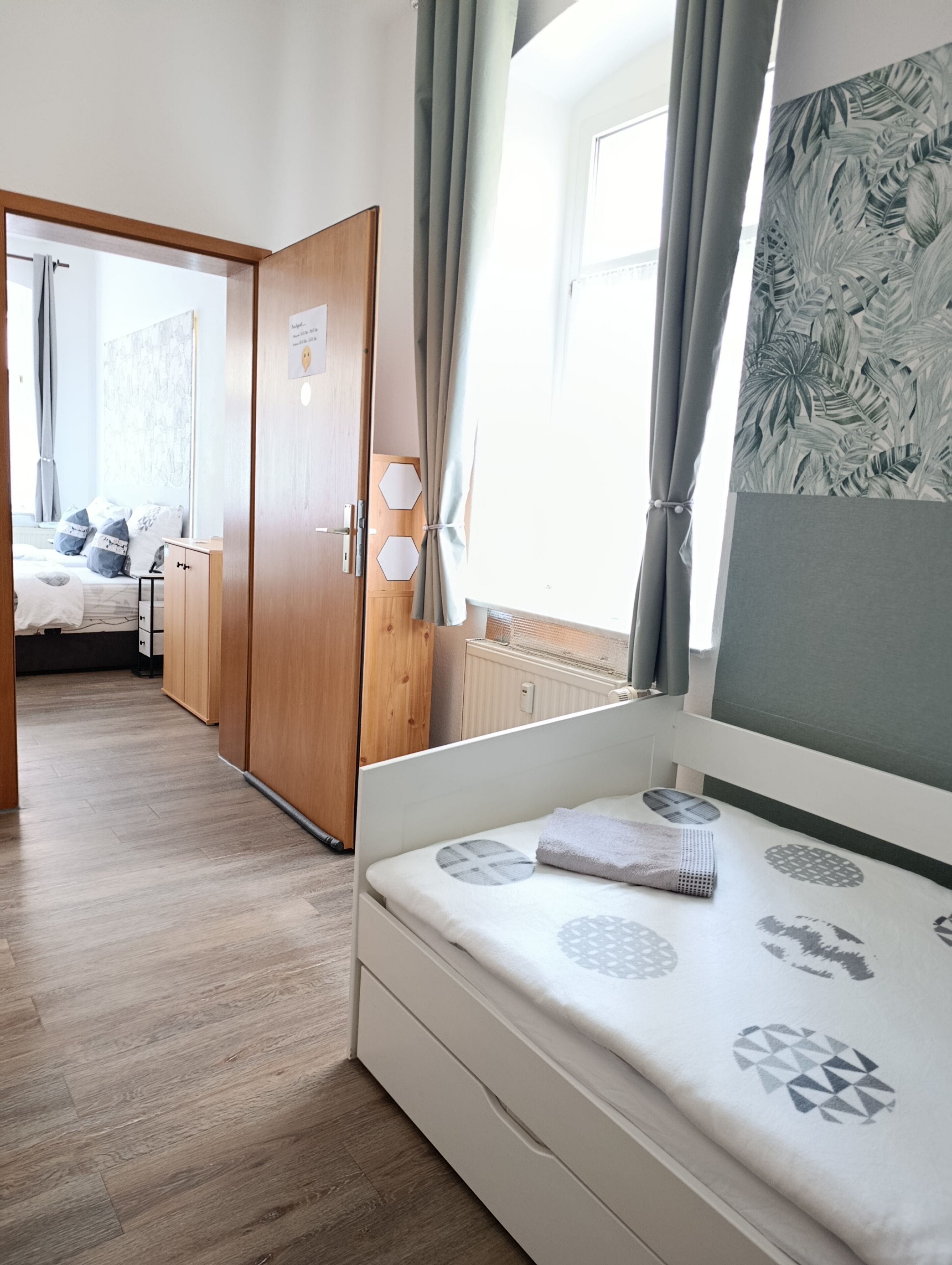 A bedroom with a bed, wooden wardrobe, and a view of another room.