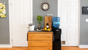 Een kamer met een houten dressoir, een waterdispenser, een klok en een potplant.