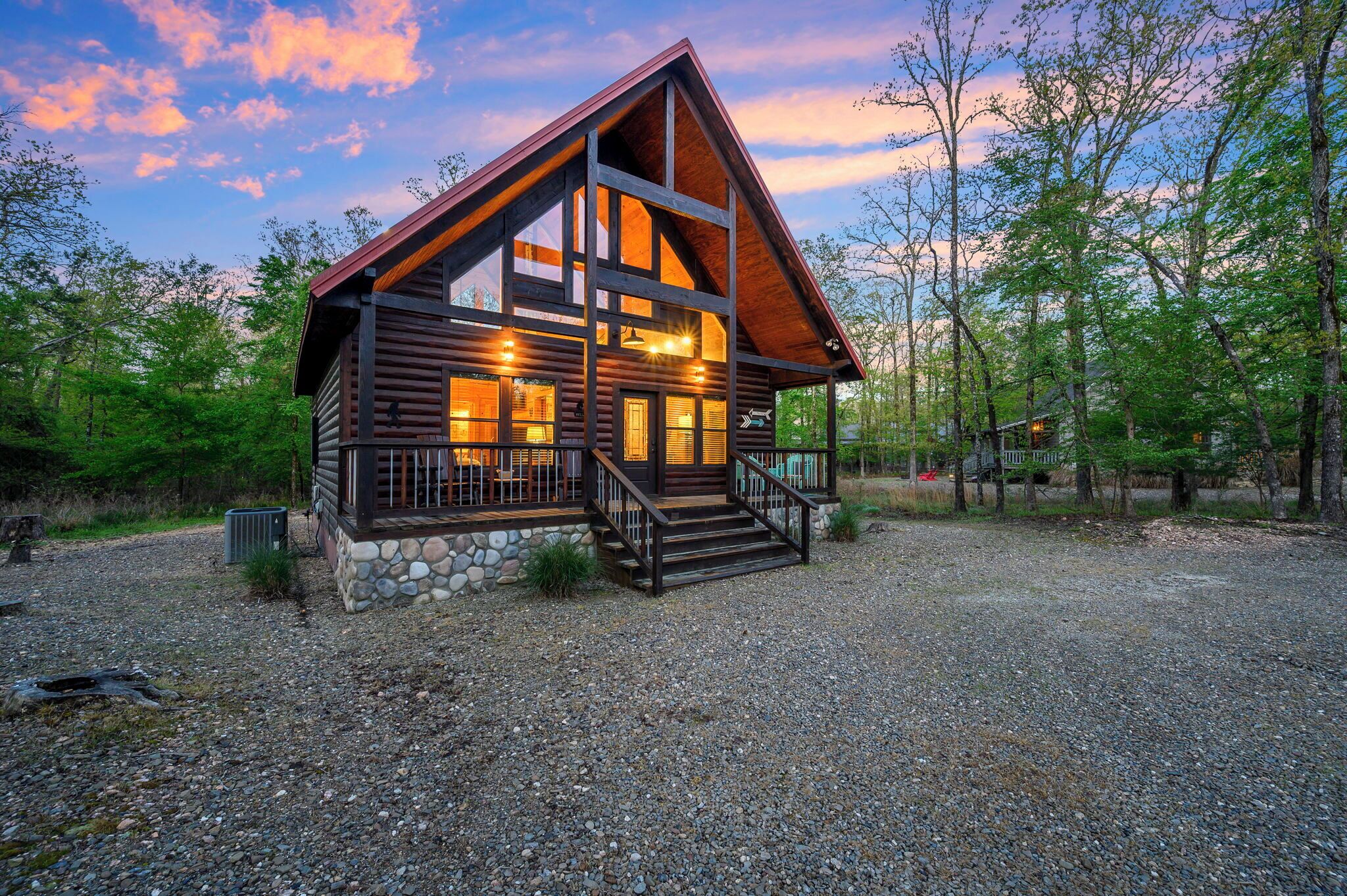 A log cabin with a stone foundation, large windows, and a wooden deck.