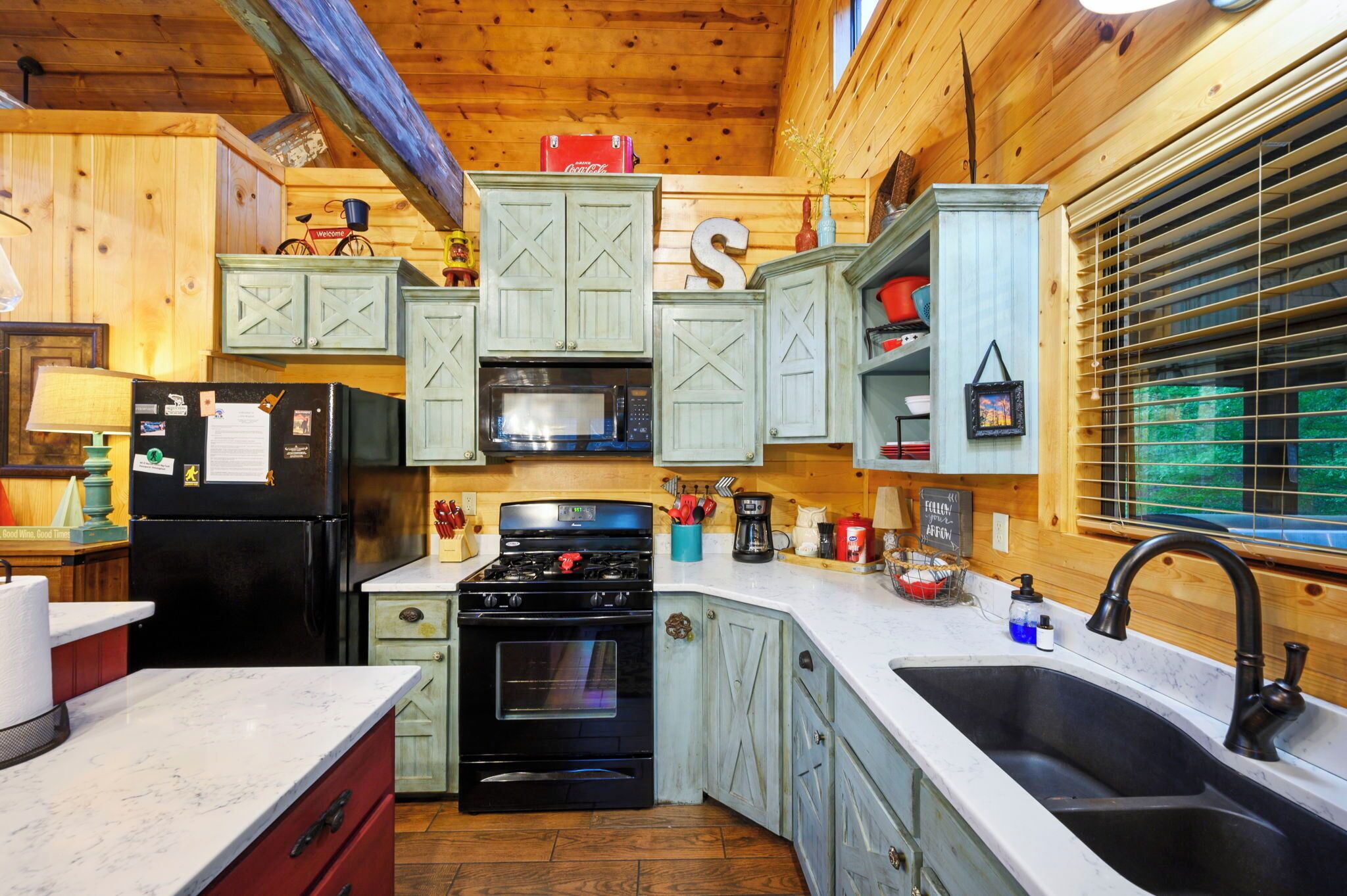 A compact kitchen with wooden cabinets, a black refrigerator, a stove, and a microwave.