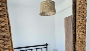 Una camera da letto con un letto, cuscini, un comodino, una lampada e una testiera in tessuto.