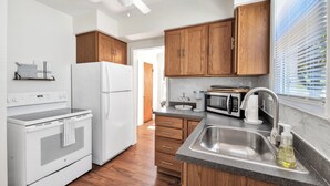 Una cucina moderna con mobili in legno, un frigorifero bianco, un forno, un microonde e un lavello con dispenser di sapone.
