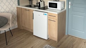 A compact kitchen with a refrigerator, microwave, sink, and wooden cabinets. - Renovated studio with wifi-center of town and beach on foot (Cabourg)