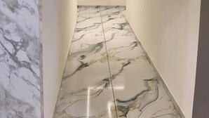 A hallway with marble flooring and a ceiling light fixture. - Hotel 7 CR (Ahmedabad)