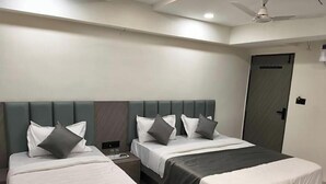 A hotel room with two beds, a ceiling fan, and a door labeled 'Check-in.' - Hotel 7 CR (Ahmedabad)