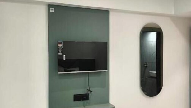 A room with a built-in TV shelf, a bench, and a mirror on the wall. - Hotel 7 CR (Ahmedabad)