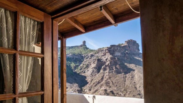 A room with a wooden ceiling, a window with curtains, and a view of a rocky mountain. - Casa Rural Pepita - Gran Canaria Center - Tejeda (Pagos de Casas Juan Gómez)