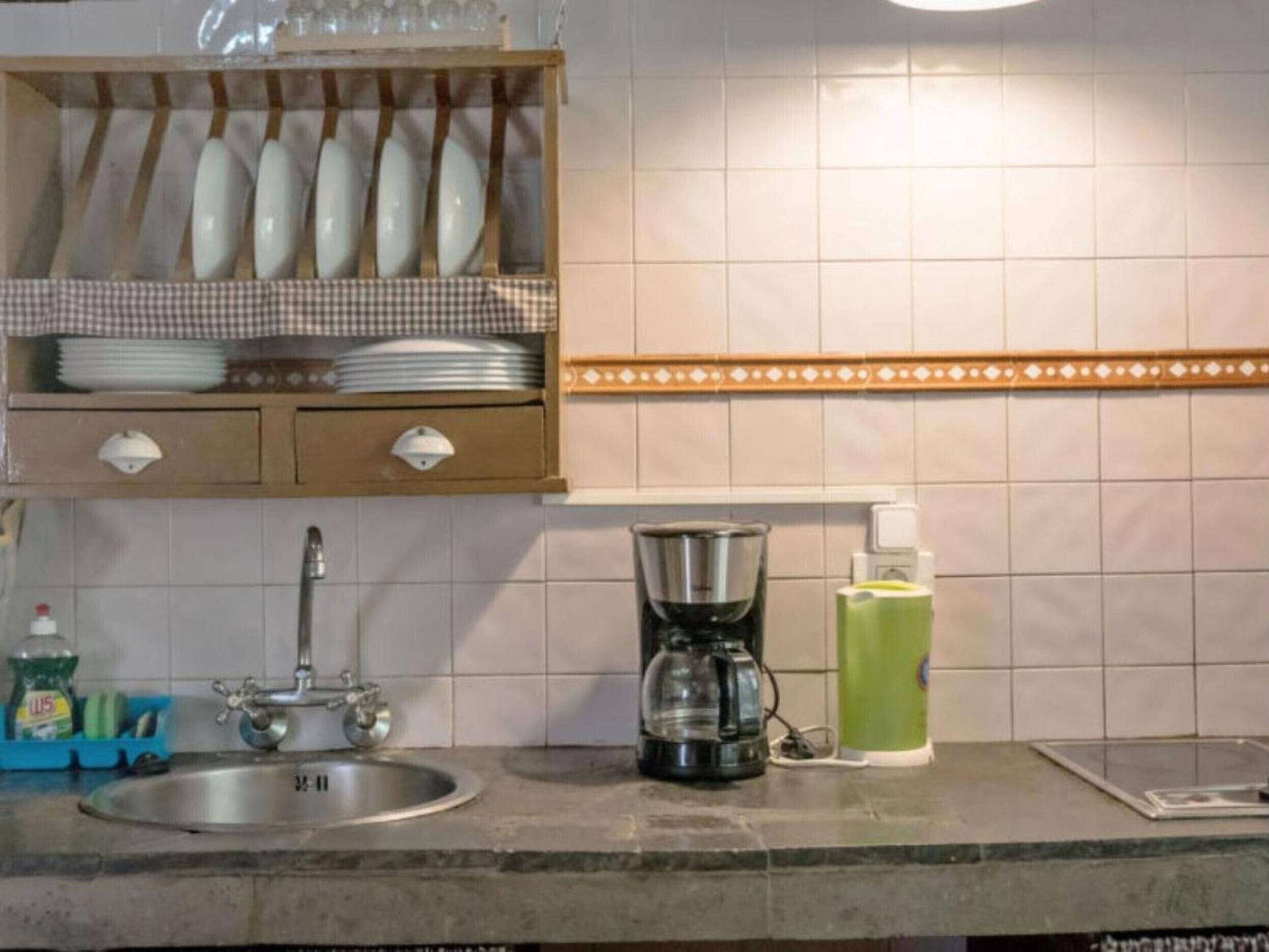 A kitchen with a sink, a coffee maker, and a dish rack.