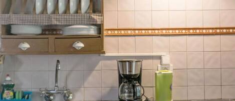 A kitchen with a sink, a coffee maker, and a dish rack.