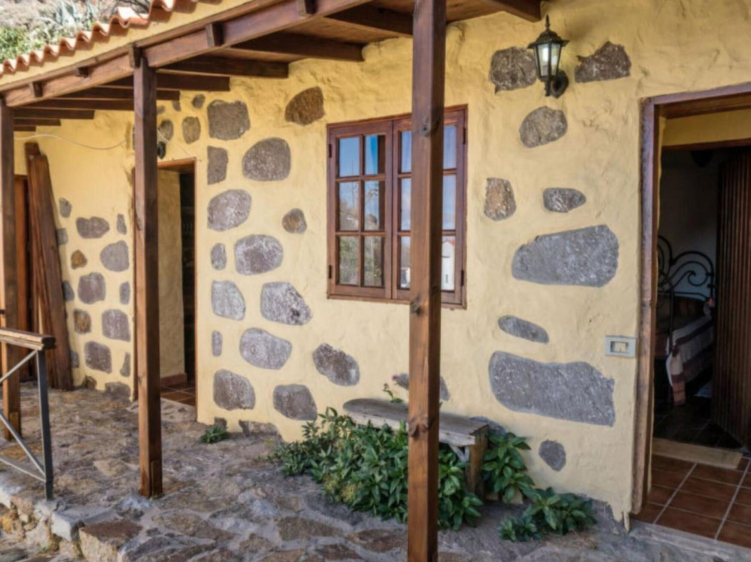 A rustic stone building with a wooden porch, a window, and a door.