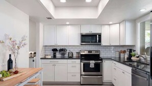 Una cocina moderna con armarios blancos, electrodomésticos de acero inoxidable y una mesa de comedor de madera.