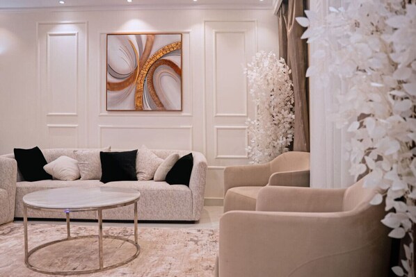 A modern living room with a beige sofa, a round coffee table, and a large abstract painting on the wall.